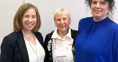 Three people pose with an award.