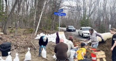 People fill sandbags at a sandbag station.