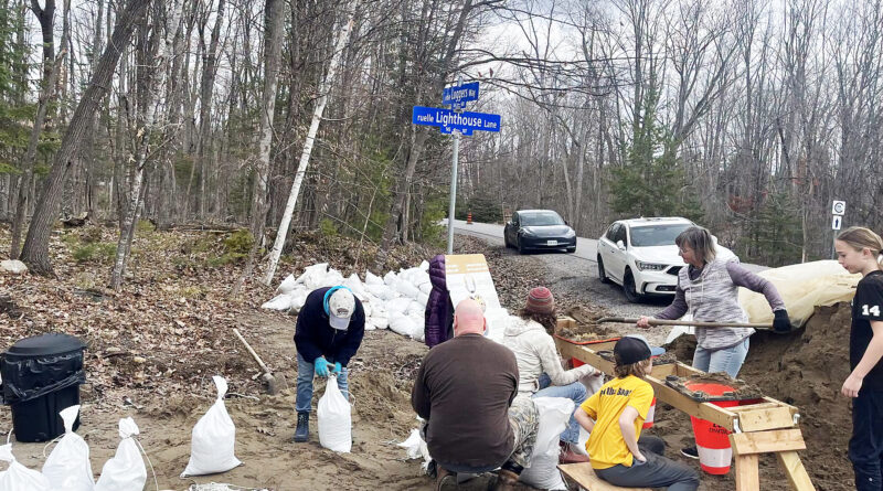 People fill sandbags at a sandbag station.