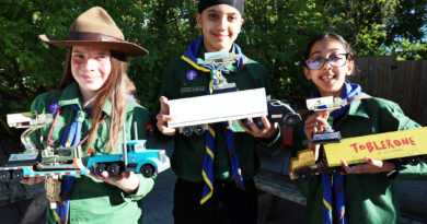 Three people pose with their racing trucks.