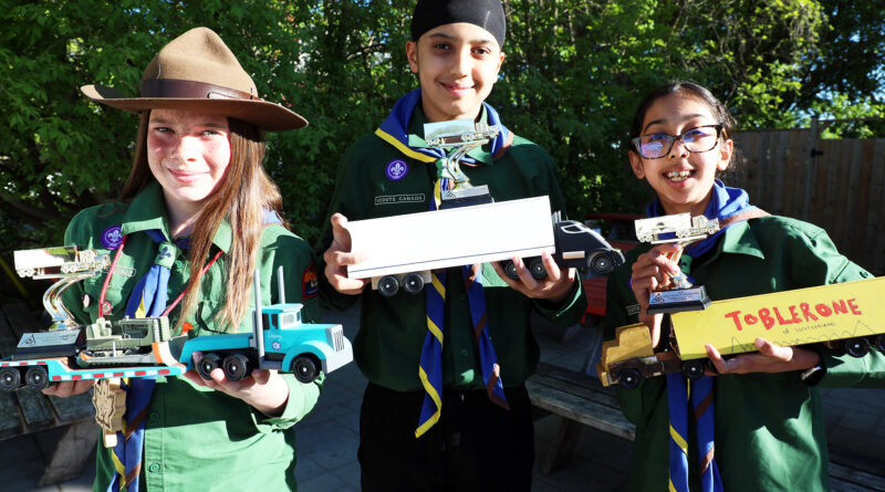 Three people pose with their racing trucks.