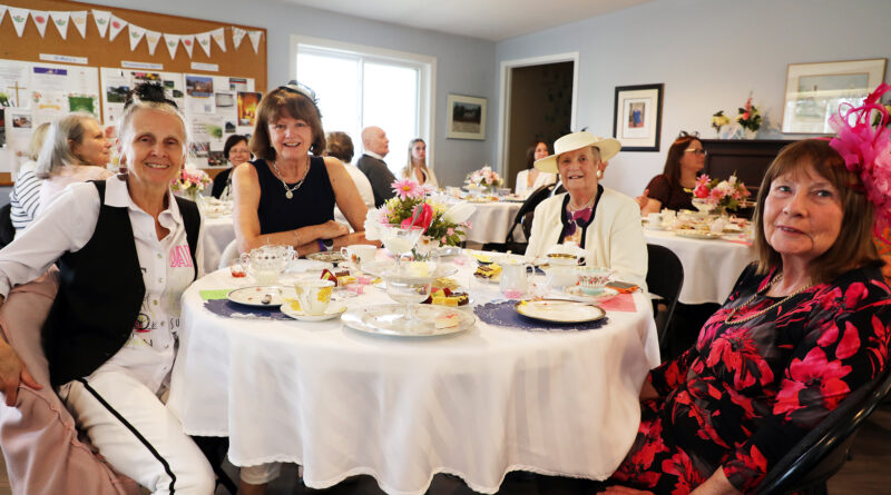People having tea pose for a photo.