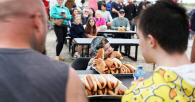 A photo of a boy eating hotdogs.