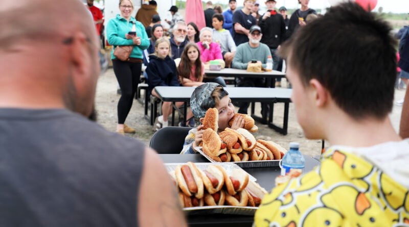 A photo of a boy eating hotdogs.