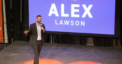 A man speaks in front of an electronic election sign.