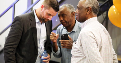 A man speaks to two others.