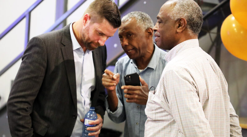 A man speaks to two others.