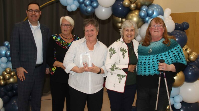 A group poses for a phot owith an award.