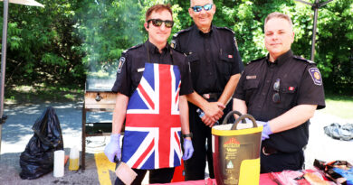 Three firefighters pose by a barbecue.
