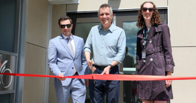 Three people cut a ribbon.