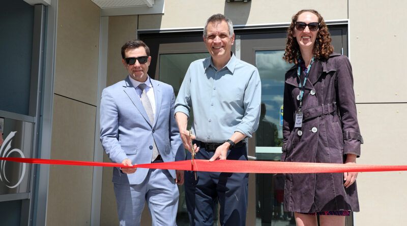 Three people cut a ribbon.