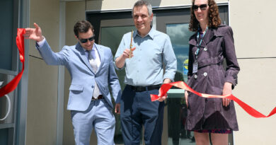 Three people cut a ribbon.