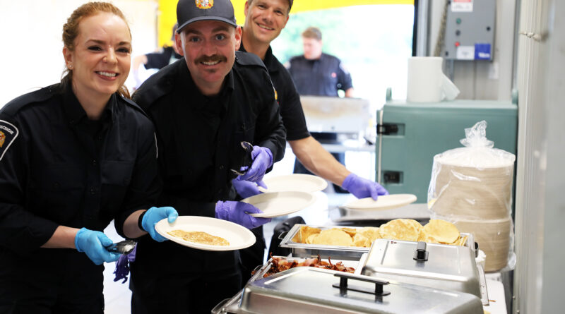 Three firefighters serve breakfast.