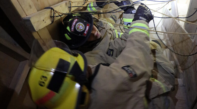 Two firefighters goind down stairs feet first.