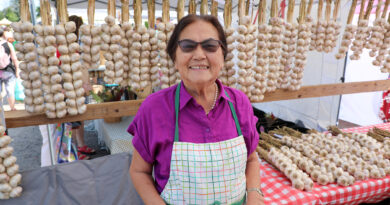 A woman poses in front of garlic.