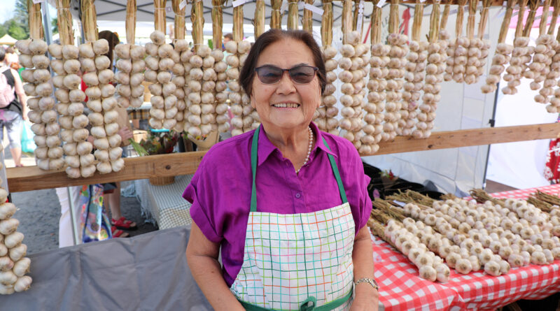 A woman poses in front of garlic.