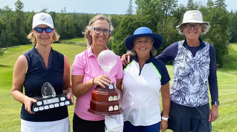 Four people pose with trophies.