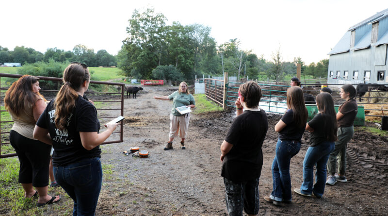 A group of people talk at a farm.